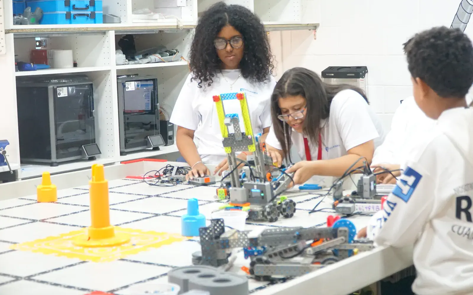 Estudiantes prueban varios robots VEX en una mesa de trabajo del laboratorio VST.